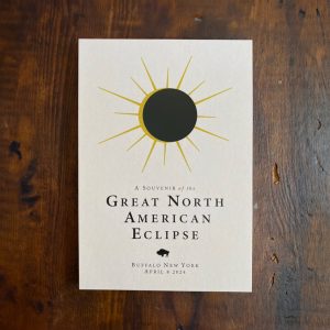 Post card featuring retro inspired eclipse art with black circle moon and starburst sun coming from behind. The post card reads "A souvenir of the Great North American Eclipse, Buffalo, NY April 8, 2024"