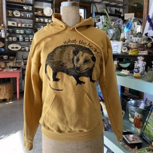 Mustard yellow sweatshirt on a vintage mannequin in a made in buffalo gift shop with a black illustration of an opossum. Text on shirt reads "What the heck!